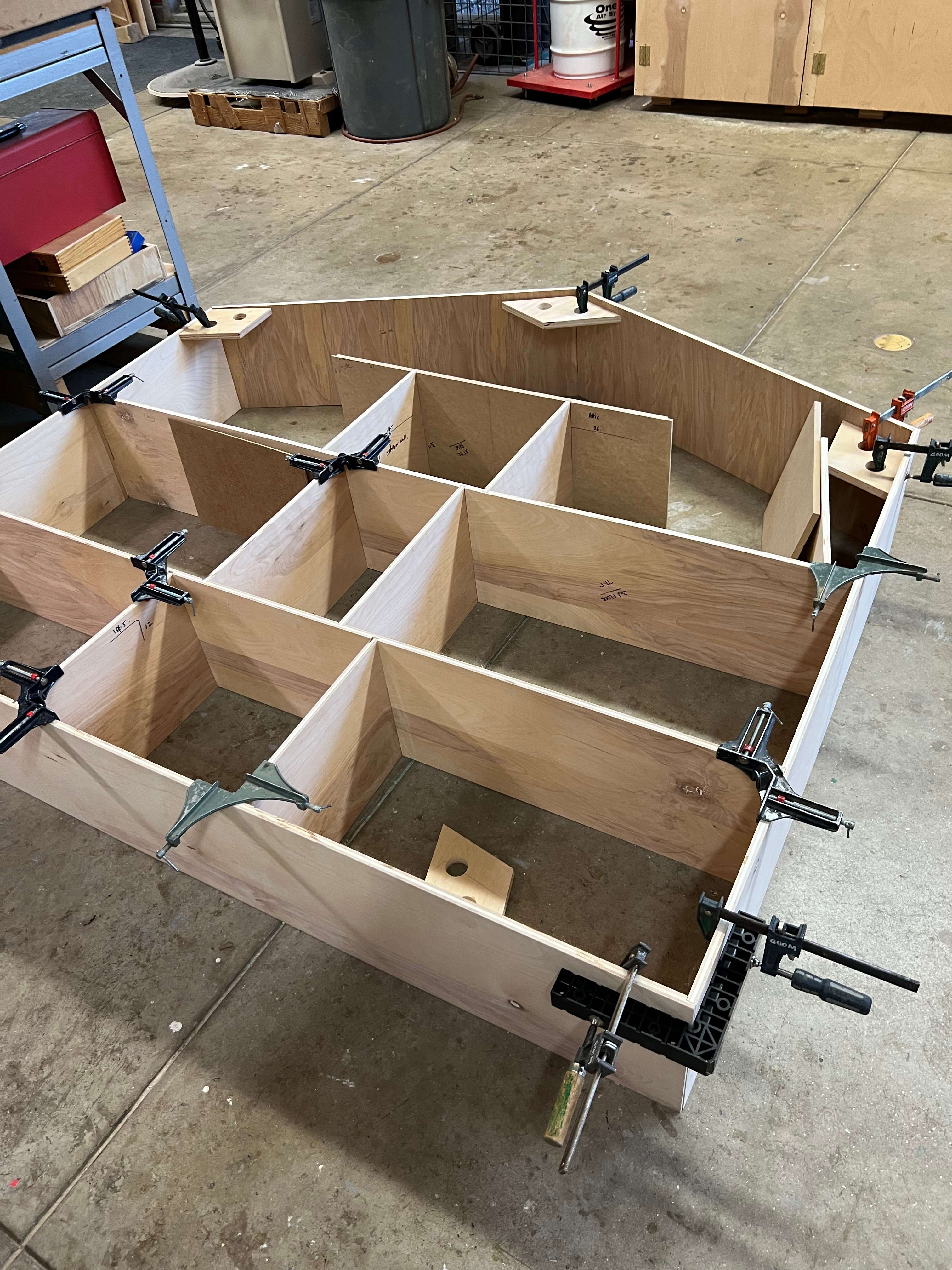 Lover House initial construction in woodshop showing wooden frame with clamps